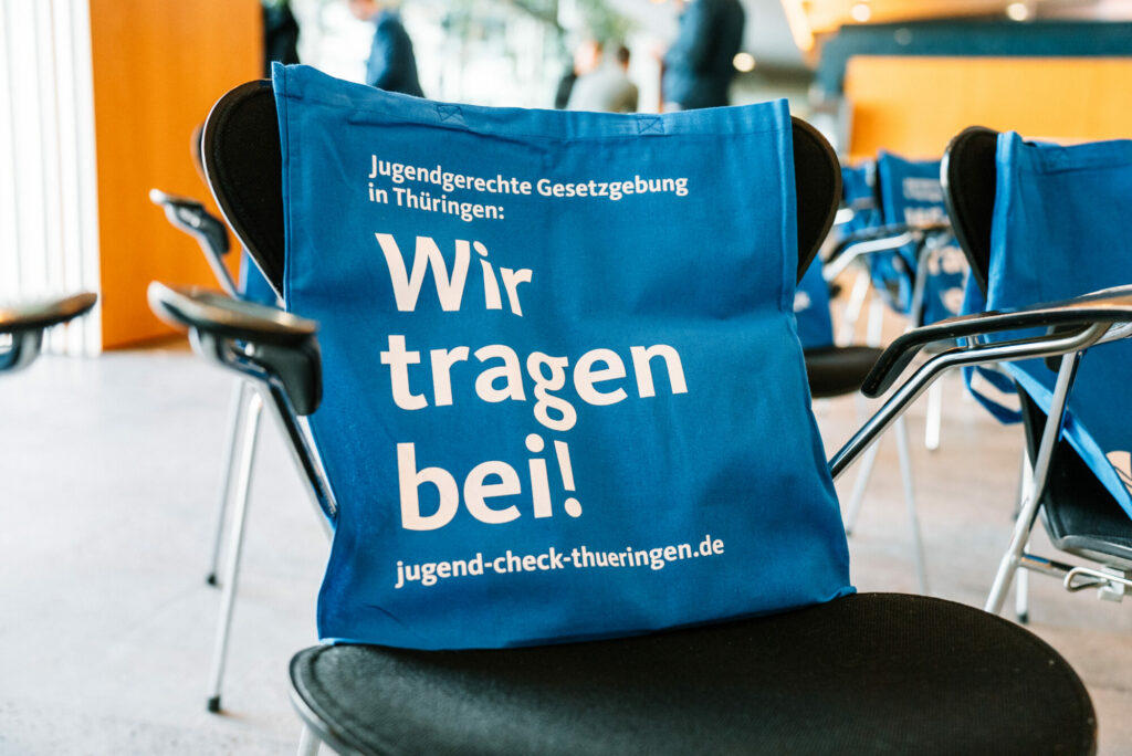 Eine blaue Tasche mit der Aufschrift "Jugendgerechte Gesetzgebung in Thüringen: Wir tragen bei! jugend-check-thueringen.de"